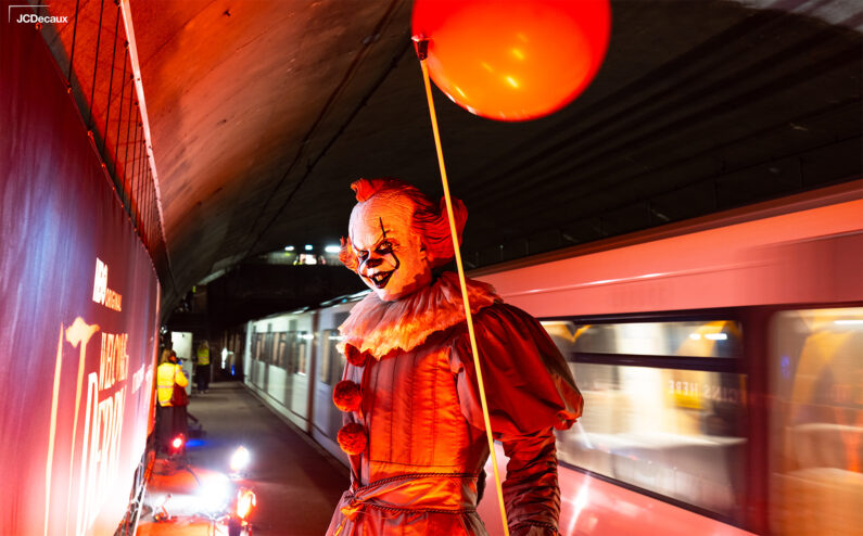 Klovnen Pennywise står på Valkyrien Stasjon mens T-banen kjører forbi.