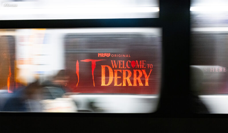 Banner med "IT: Welcome to Derry" synes gjennom vinduet på T-banen.